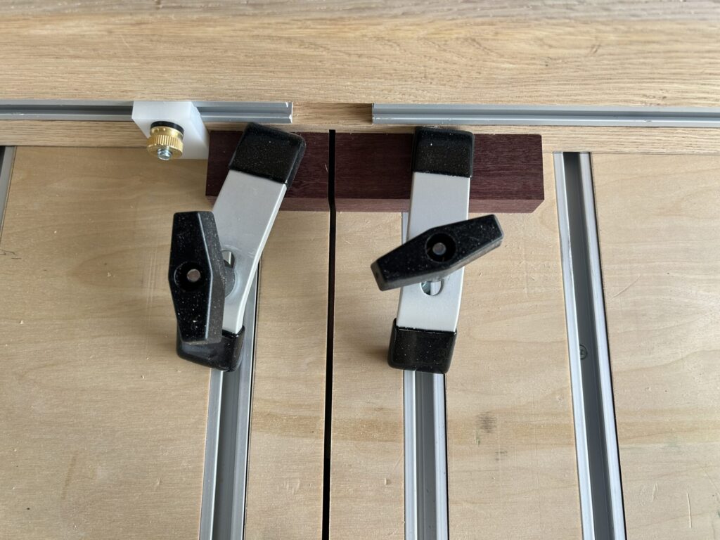 Hold-downs holding a small block of purpleheart to cut to size